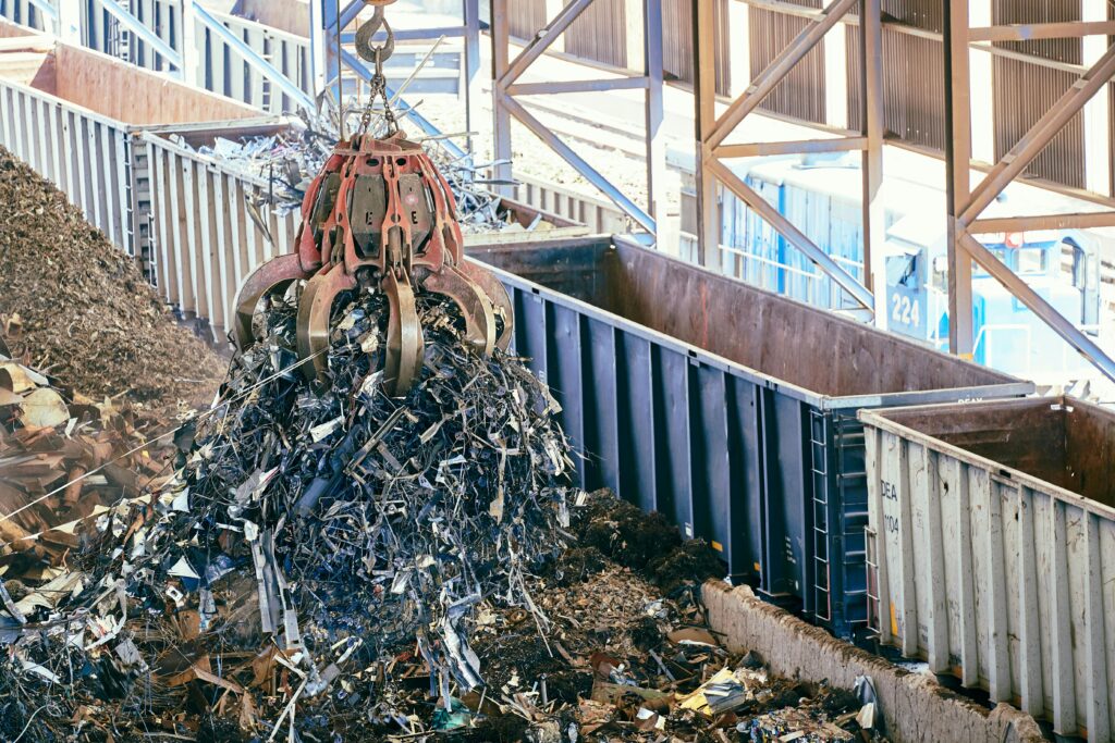 An industrial claw crane lifts metal scrap in a recycling facility, showcasing efficient waste management.